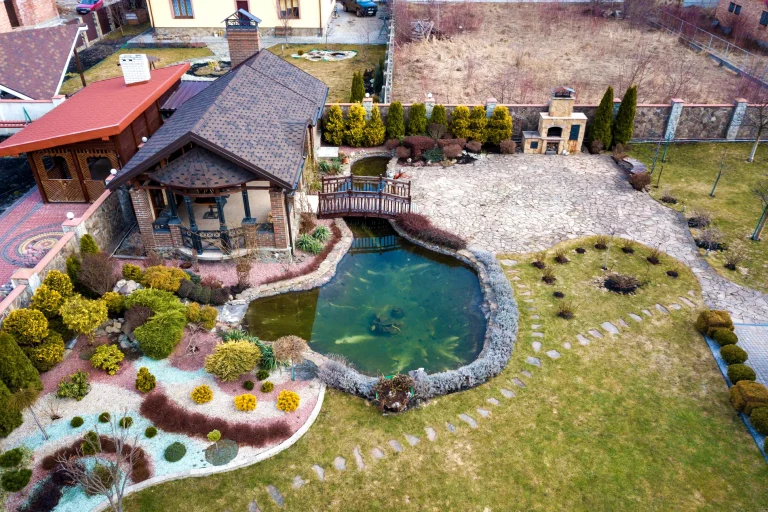 An aerial view of a house with a pond and beautiful landscape.